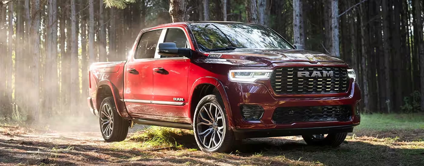 A red 2025 Ram 1500 is shown parked in a forest.