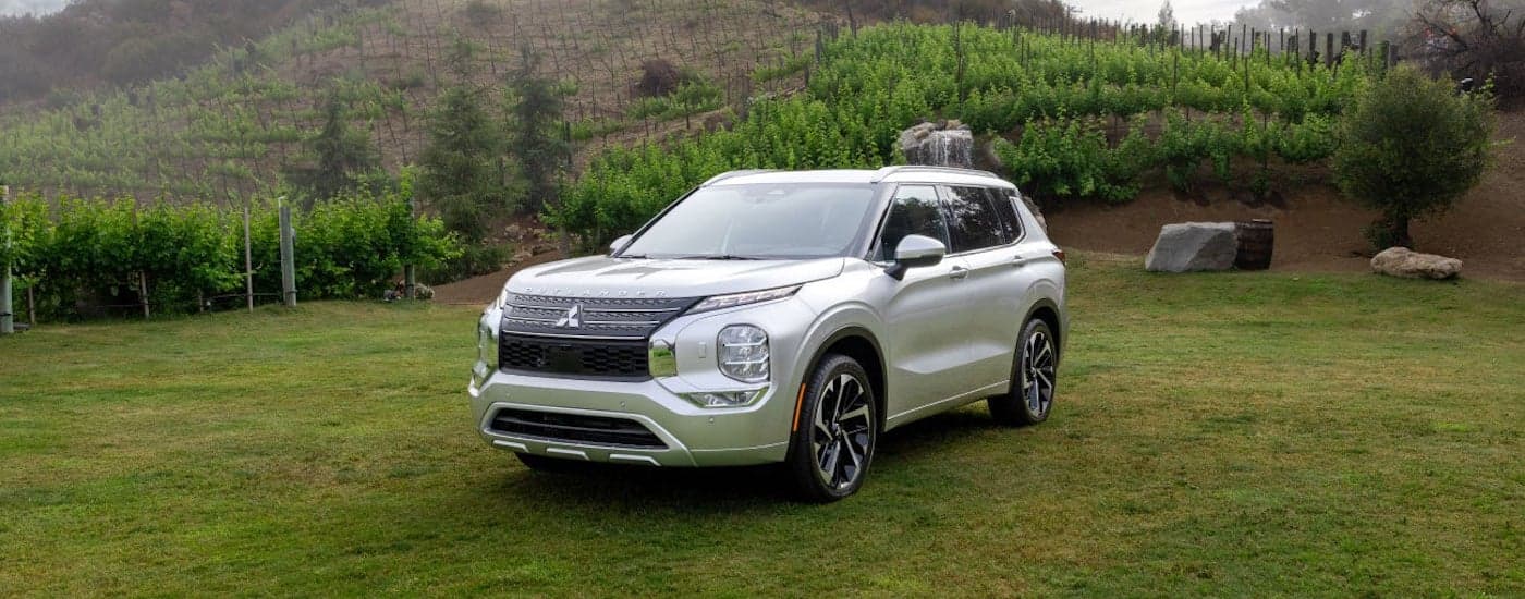 A white 2024 Mitsubishi Outlander is shown from the front at an angle.