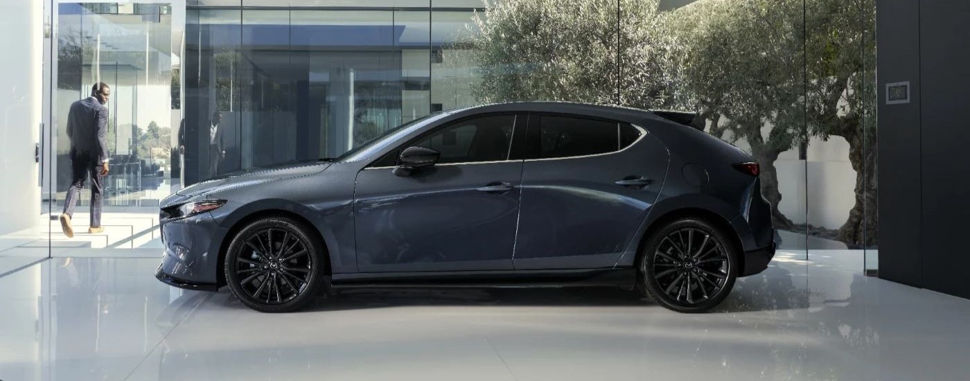 A grey 2024 Mazda3 Sport for sale is shown at a dealership.