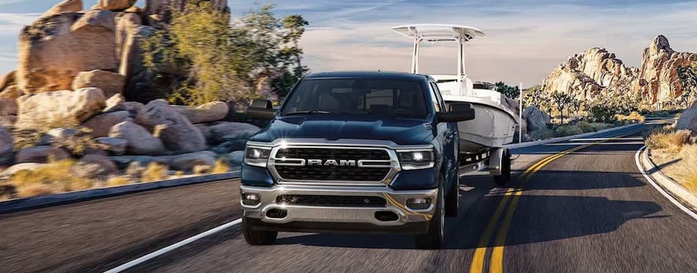 A grey 2023 Ram 1500 is shown from the front while towing a boat.