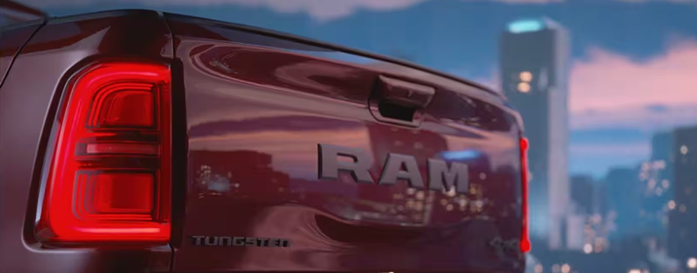 A close-up shows the tailgate on a red 2025 Ram 1500 Tungsten.