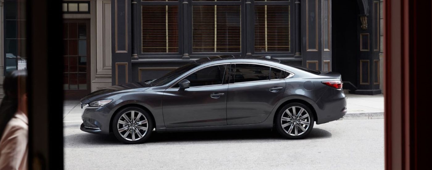 A grey 2019 Mazda6 is shown from the side parked on a city street.
