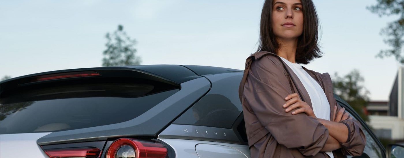A person is shown leaning against a white 2024 Mazda MX-30.