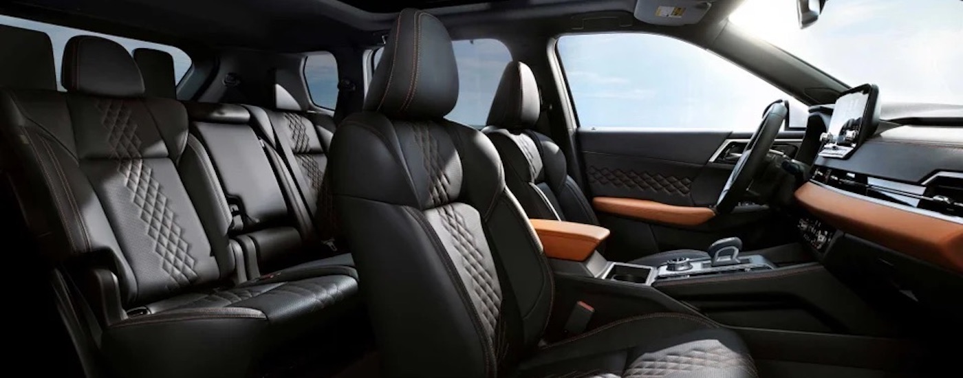 The black interior of a 2024 Mitsubishi Outlander PHEV is shown from the passenger side.