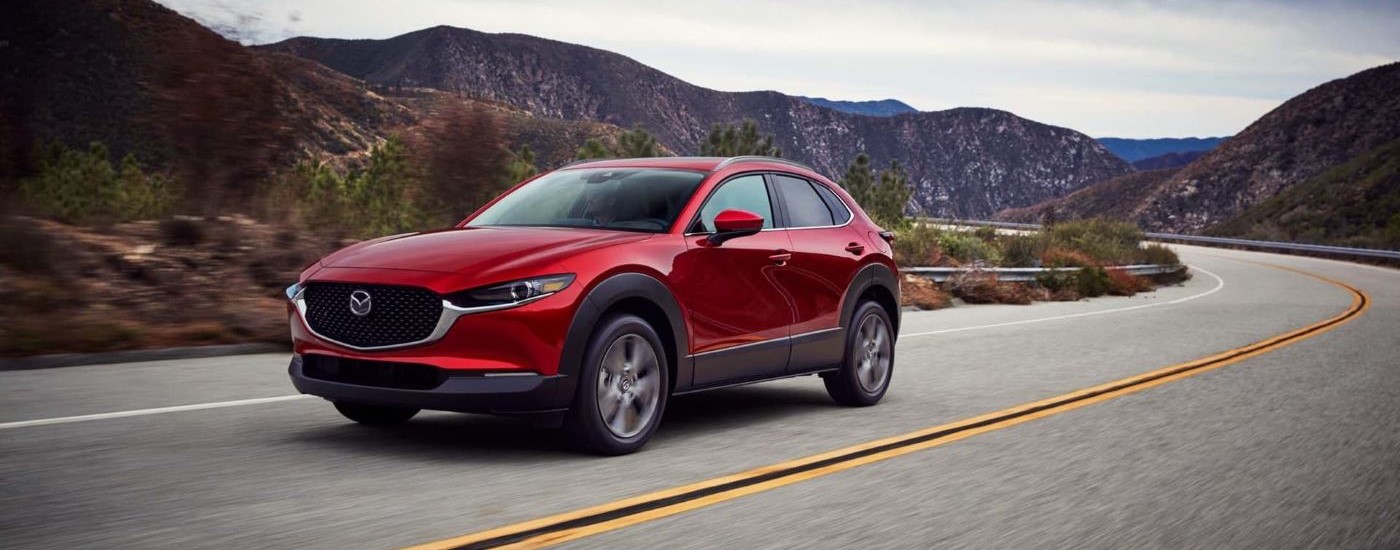 A red 2020 Mazda CX-30 is shown driving past mountains.