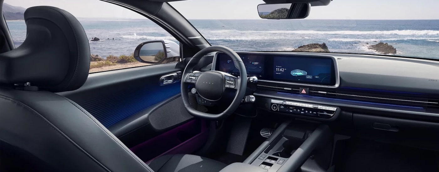 The black interior of a 2024 Hyundai IONIQ 6 is shown from the rear seats looking forward.