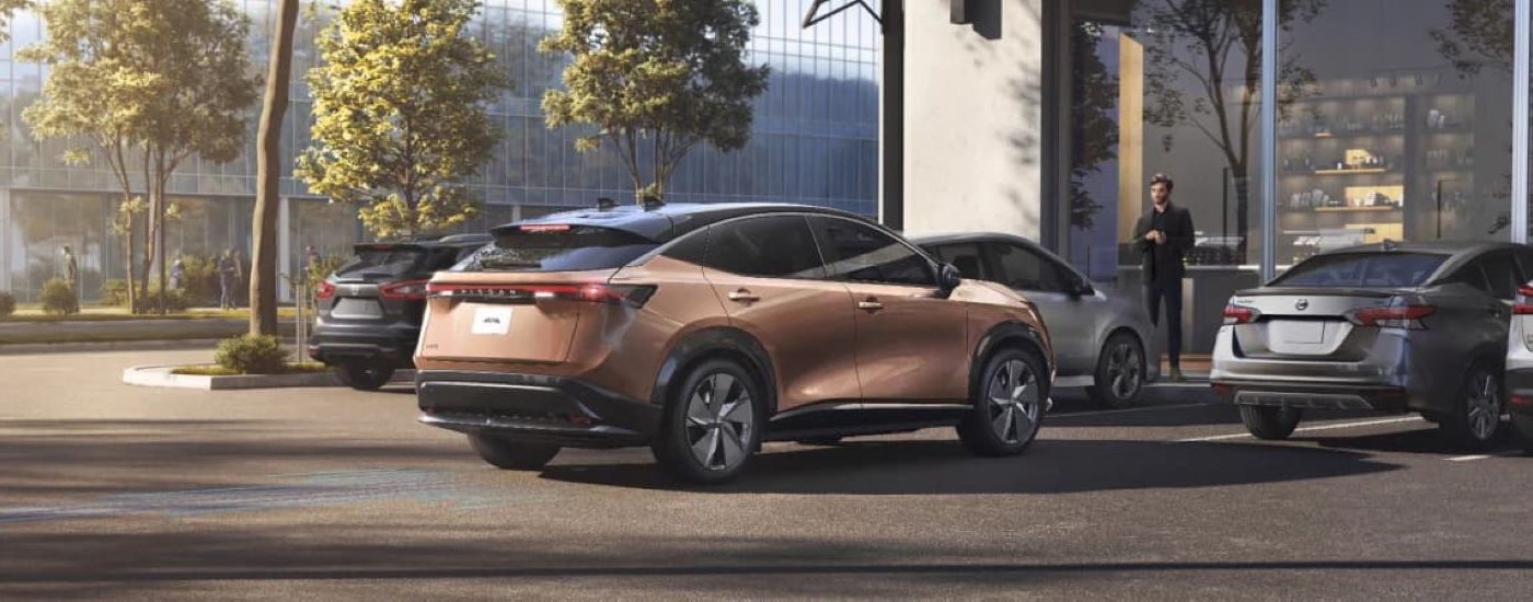 A bronze 2023 Nissan ARIYA is shown reversing from a parking spot.