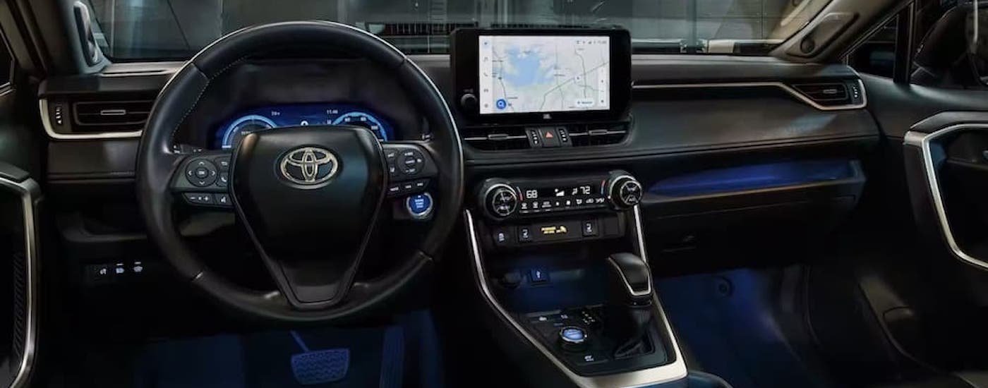 The black interior of a 2024 Toyota RAV4 is shown from the drivers seat.