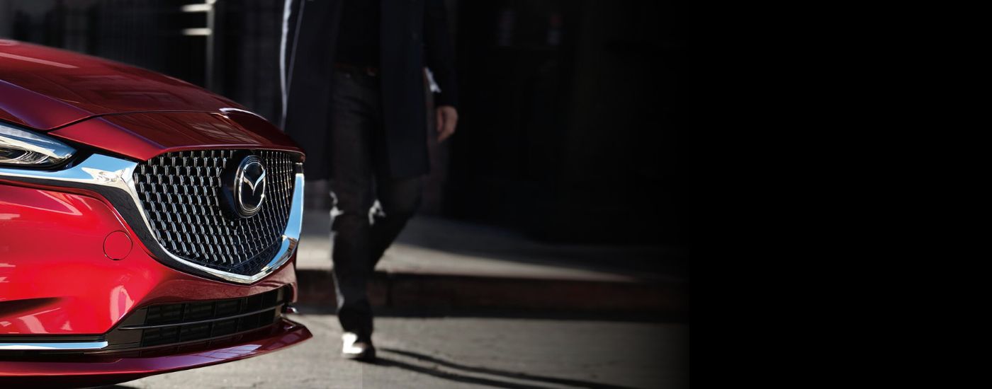 A person is shown walking past a red 2019 Mazda6.