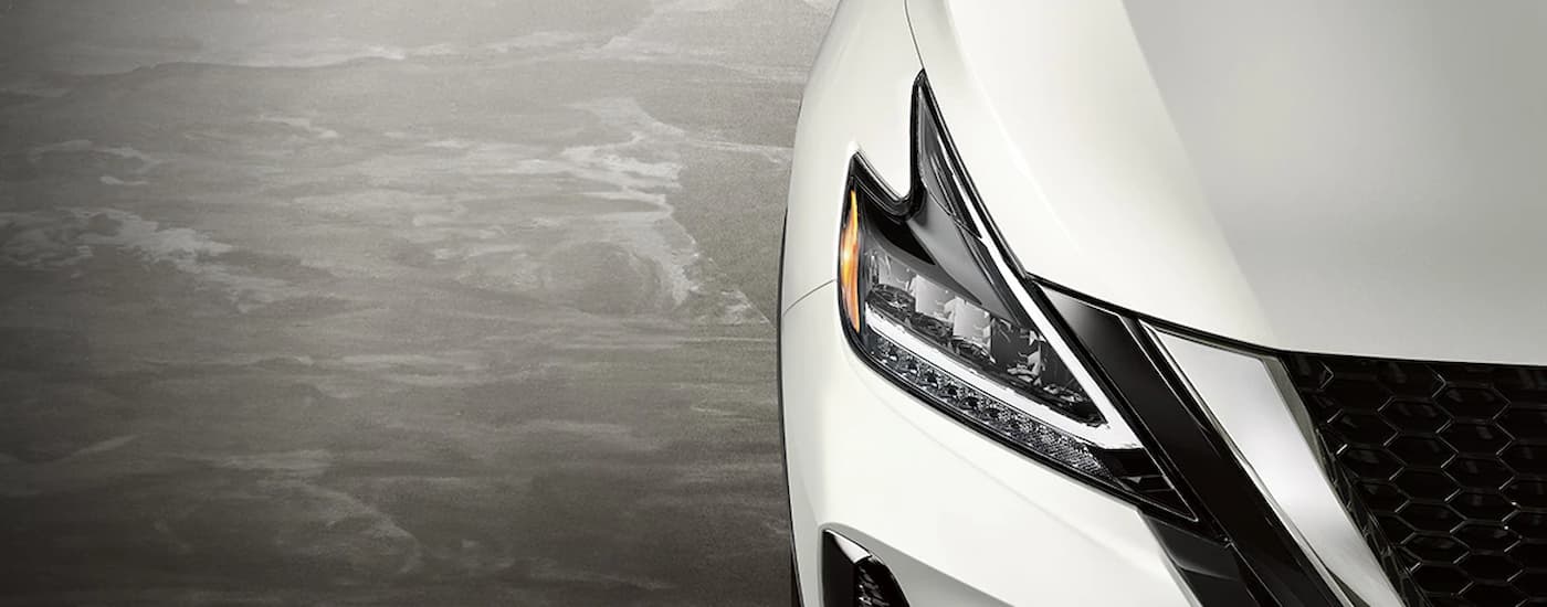 A close up of the headlight on a white 2024 Nissan Murano Platinum is shown.