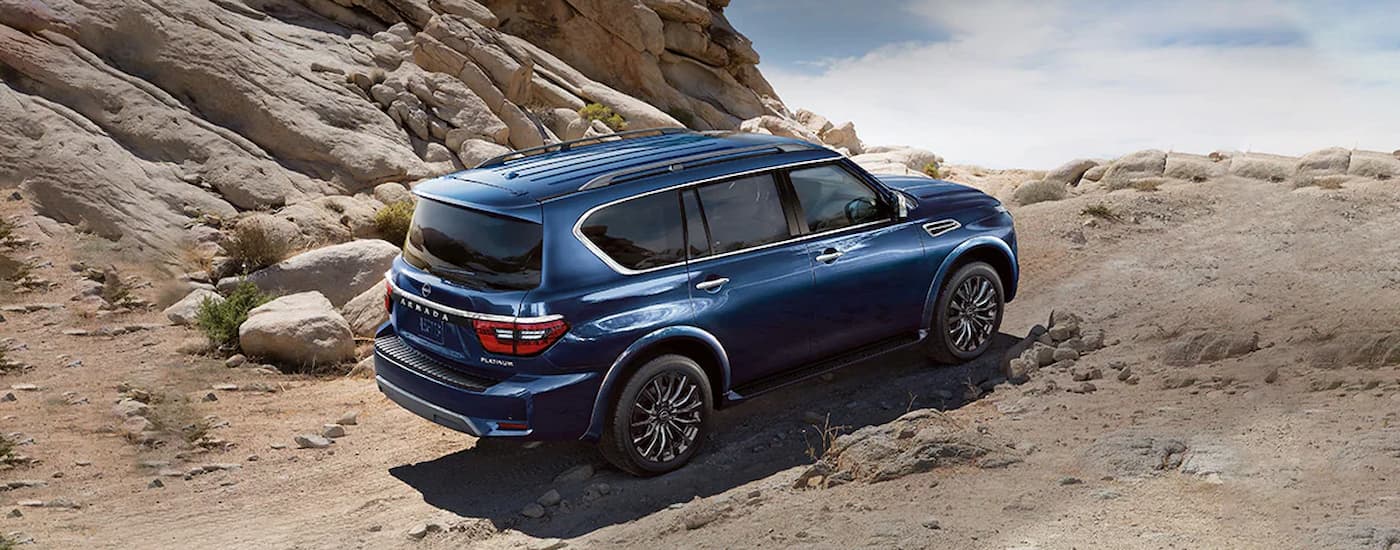 A blue 2024 Nissan Armada Platinum is shown from the side while off-roading on a rocky steep trail.
