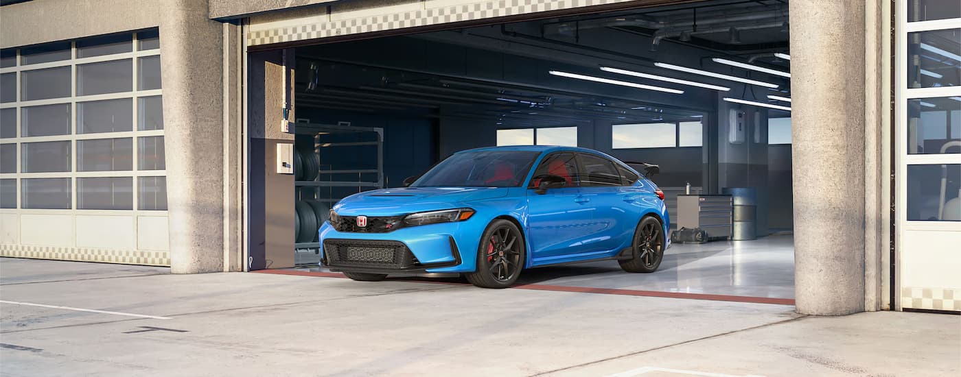 A blue 2024 Honda Civic Type R, a popular Honda Civic for sale near Folsom, is shown driving out of a garage.