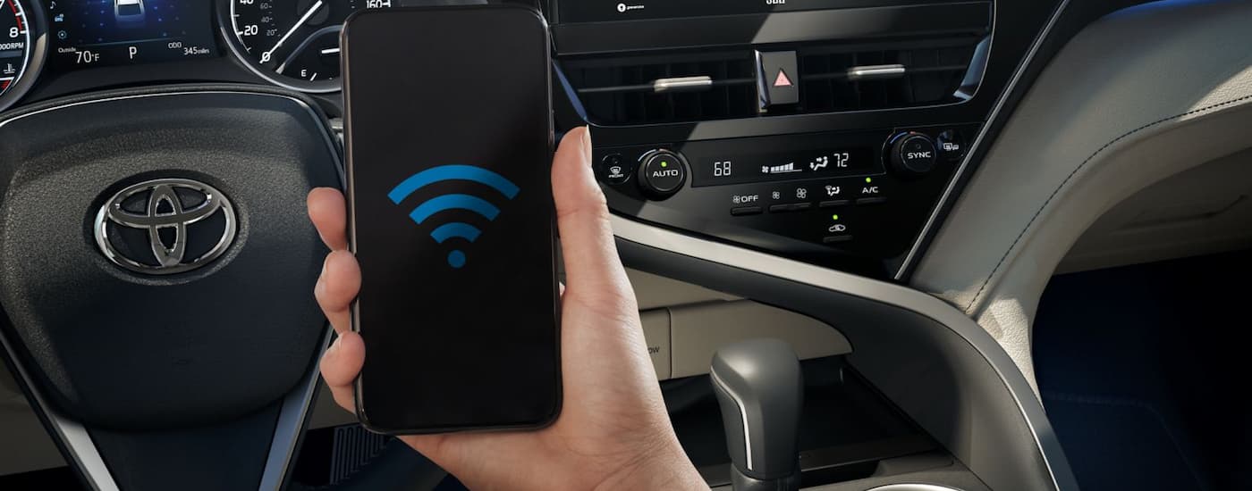 A person is using a phone in a 2024 Toyota Camry for sale.