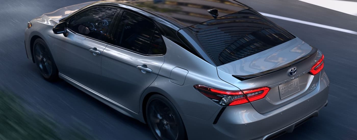 A grey 2024 Toyota Camry XSE Hybrid is shown driving on a paved road.