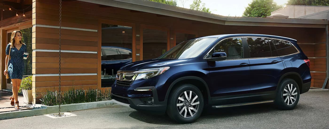 A dark blue 2022 Honda Pilot is parked in a driveway after leaving a used Honda dealer near Folsom.