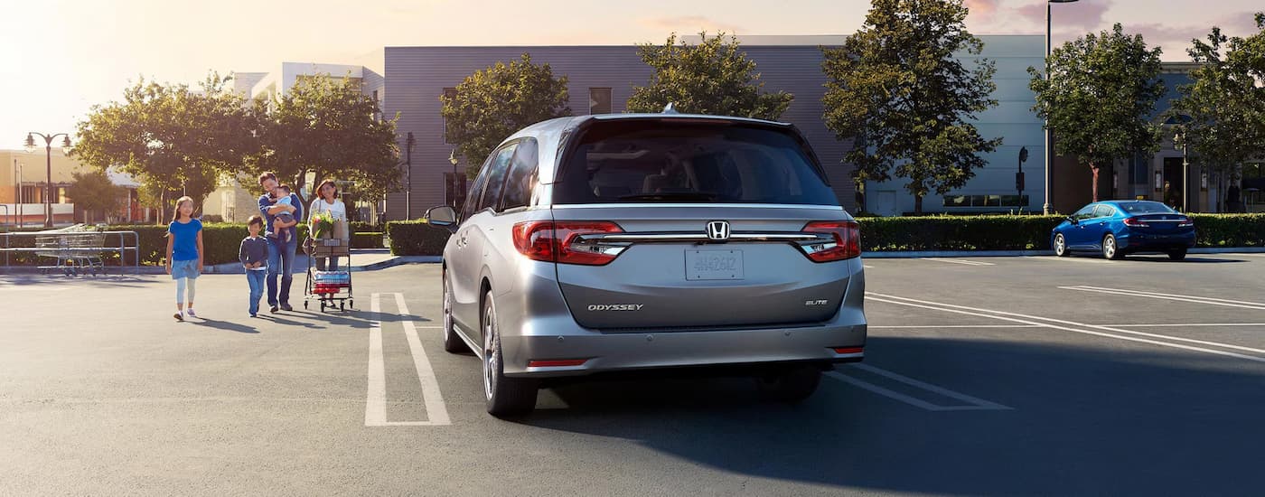 A grey 2024 Honda Odyssey Elite is parked in a lot outside of a store.