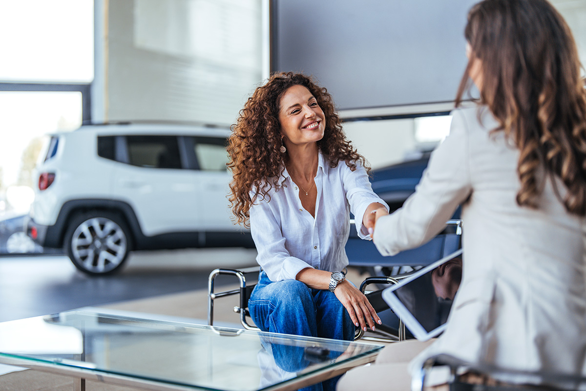 People shaking hands in car dealership