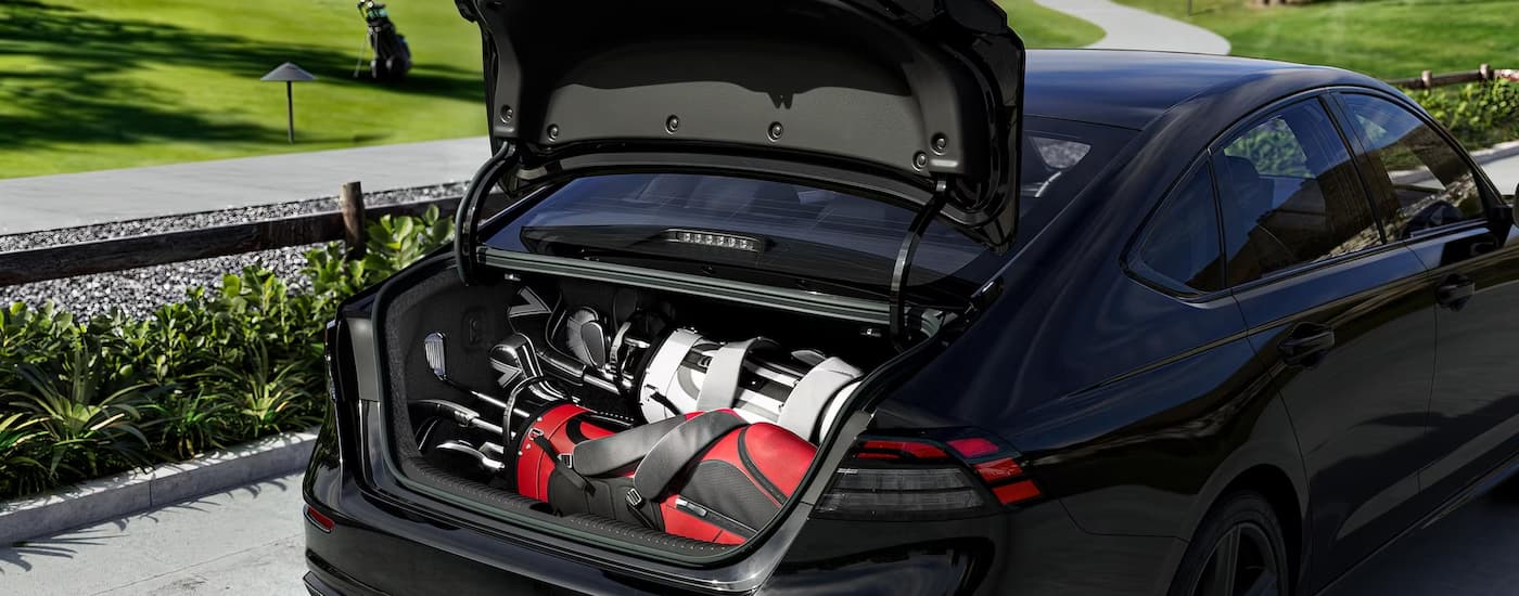 A set of golfing gear in the trunk of a black 2023 Honda Accord.