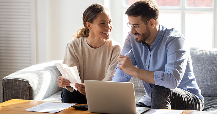 A couple on a couch infront of a laptop discussing the pre-approval application