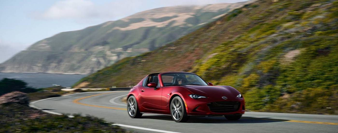 A red 2024 Mazda MX-5 Miata RF is shown from the front at an angle after leaving a Mazda dealer near Brier.