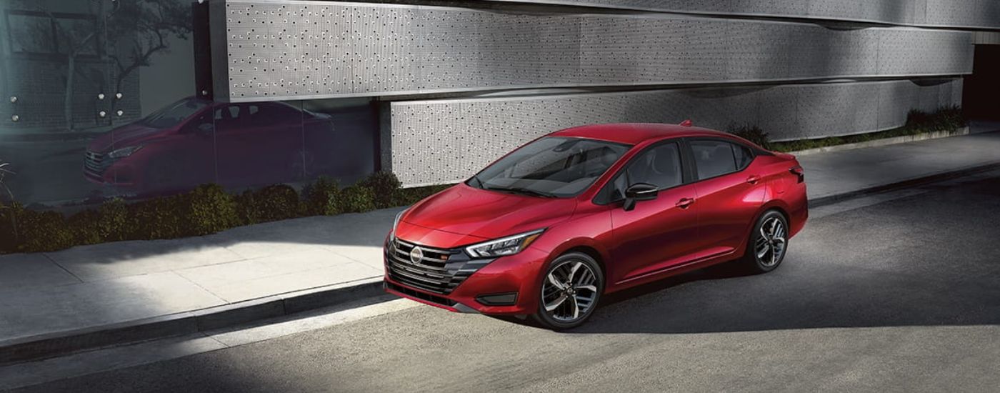 A red 2024 Nissan Versa SR is shown parked in front of a modern wall.
