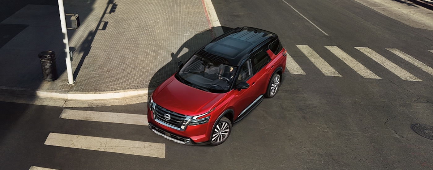 A red 2024 Nissan Pathfinder is shown from the front at a high angle after leaving an SUV dealer.