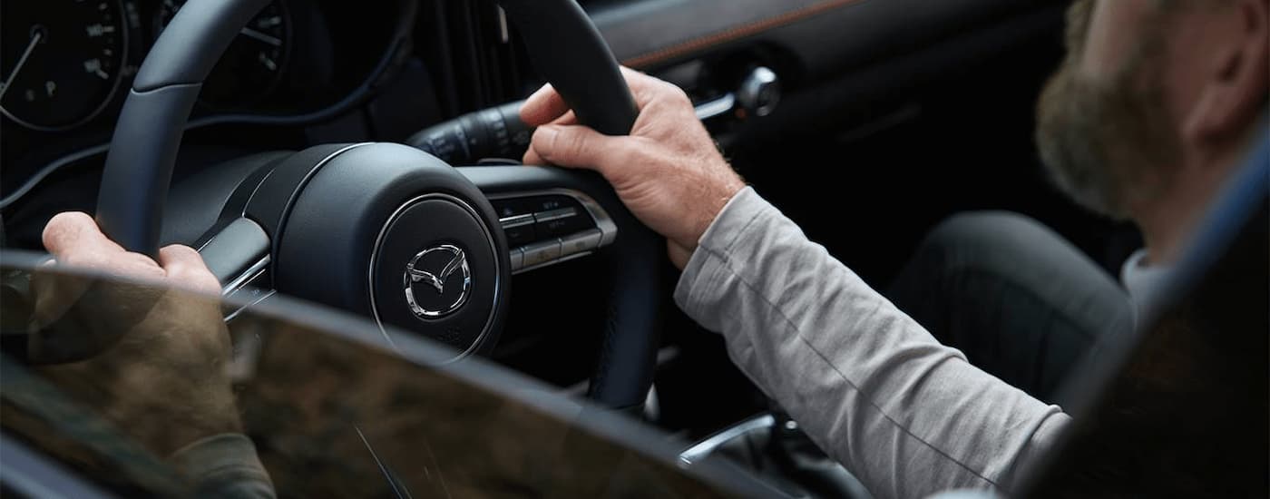 A man is driving in a 2024 Mazda CX-50.