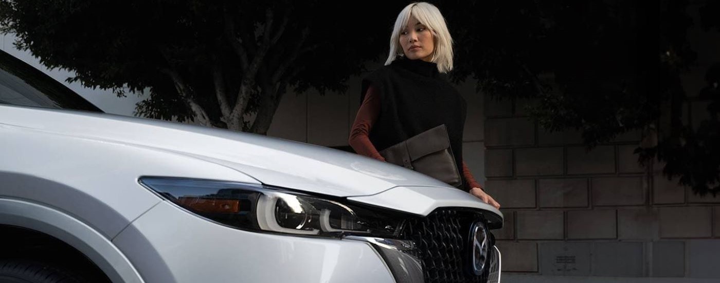 A woman is walking past a white 2024 Mazda CX-5.