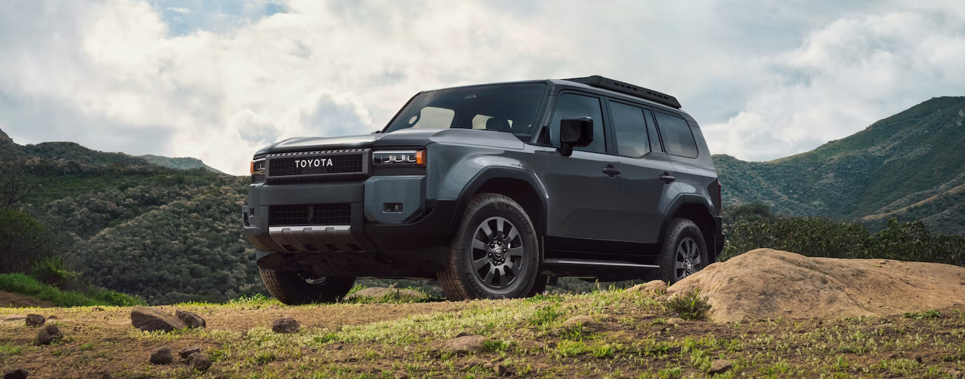 A grey 2024 Toyota Land Cruiser parked on a grassy knoll.