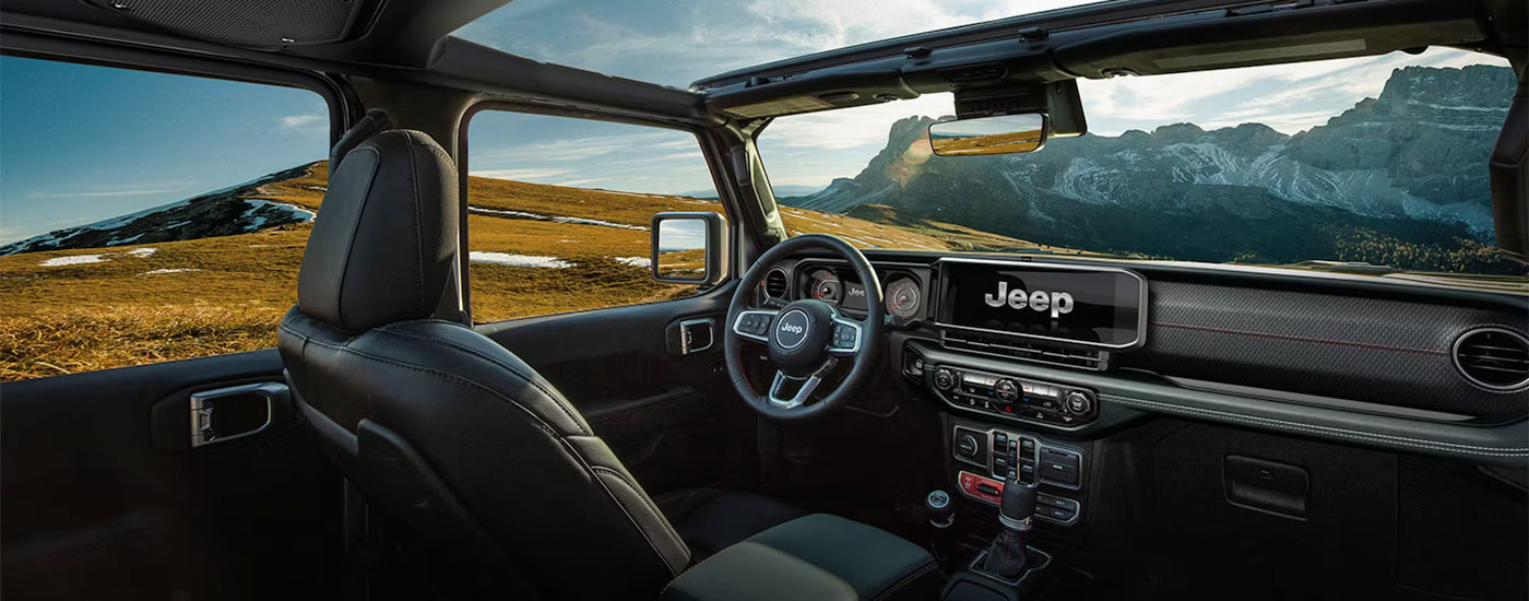 The black interior of a 2024 Jeep Wrangler parked in the mountains.