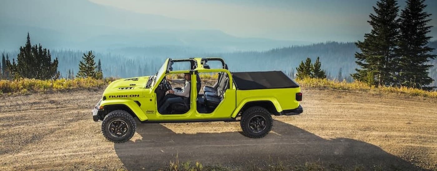 A lime green 2023 Jeep Gladiator Rubicon is shown driving on a dirt road.