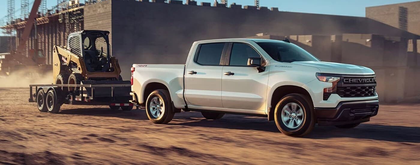 A white 2023 Chevy Silverado 1500 is shown towing a trailer.