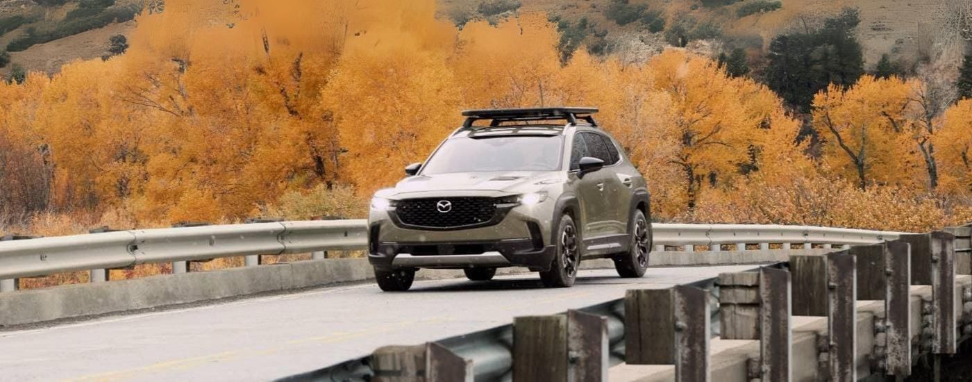 A tan 2024 Mazda CX-50 Meridian is shown driving over a bridge.