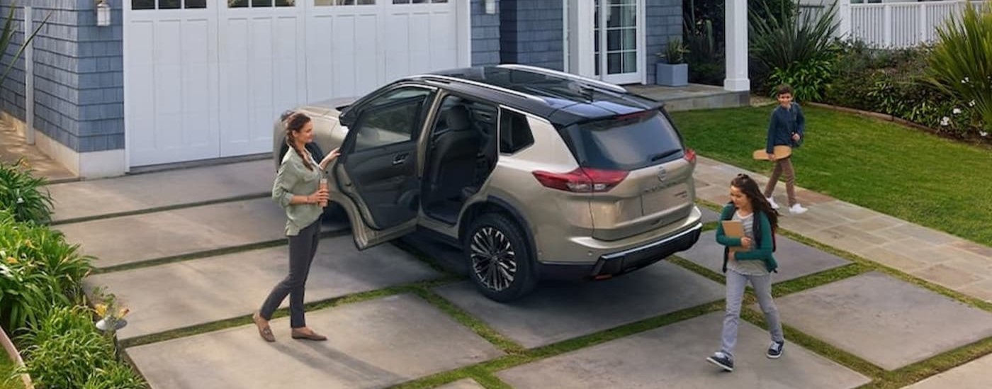 A tan 2024 Nissan Rogue Platinum is shown parked on a driveway.