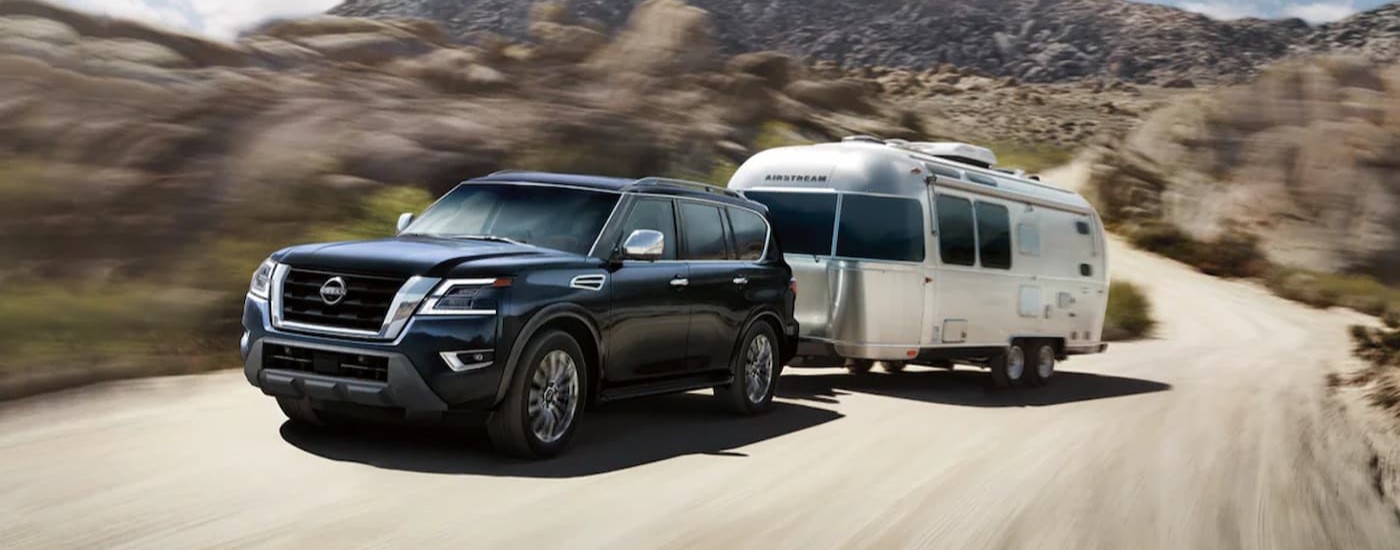 A black 2024 Nissan Armada Platinum is shown towing a trailer to a Nissan dealer near Janesville.