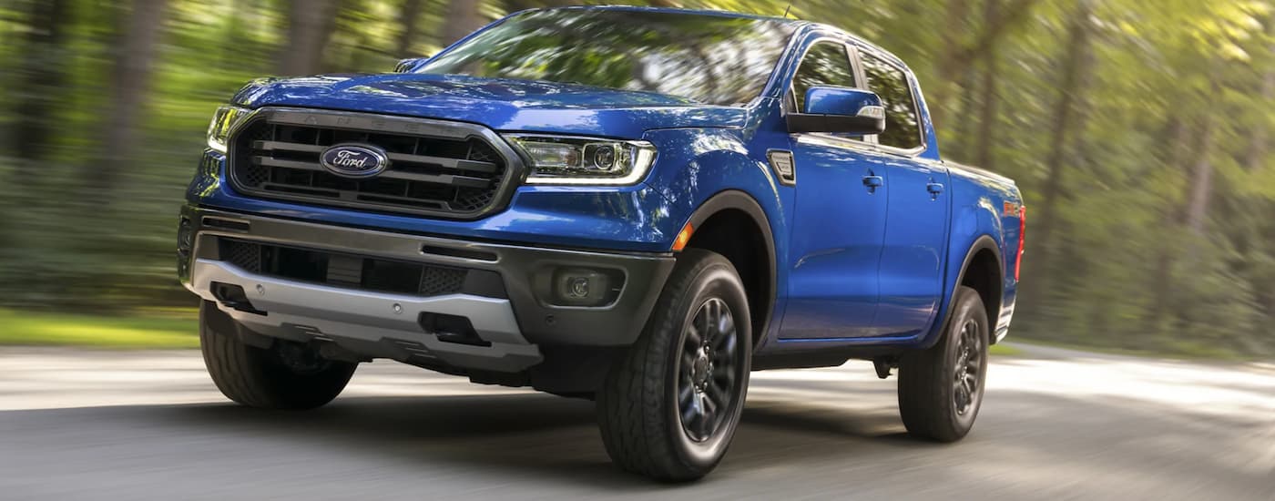 A blue 2021 Ford Ranger FX4 is shown driving to view used trucks for sale.