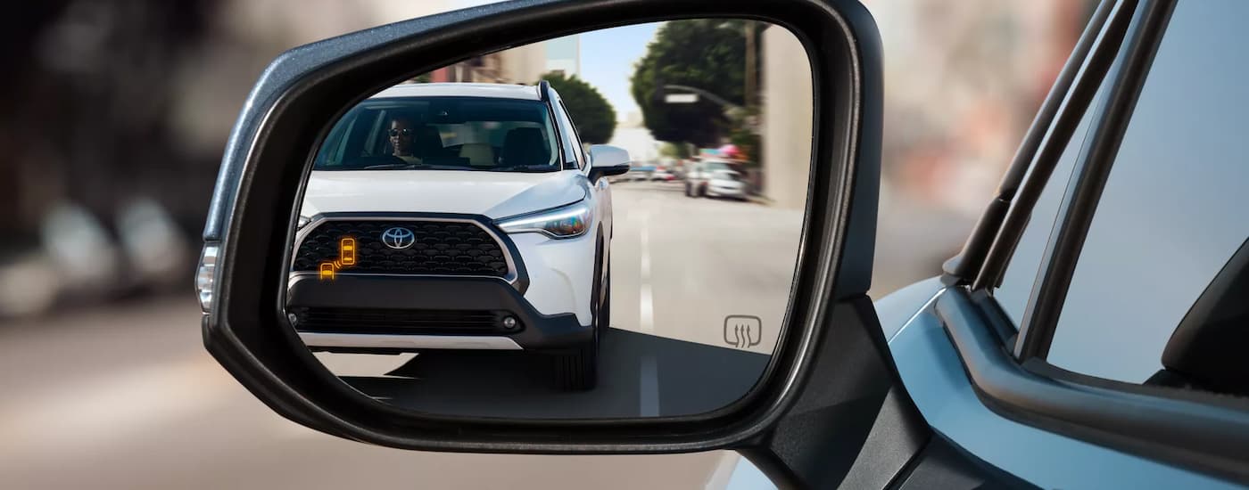 A white 2024 Toyota Corolla Cross in the side mirror of an SUV.