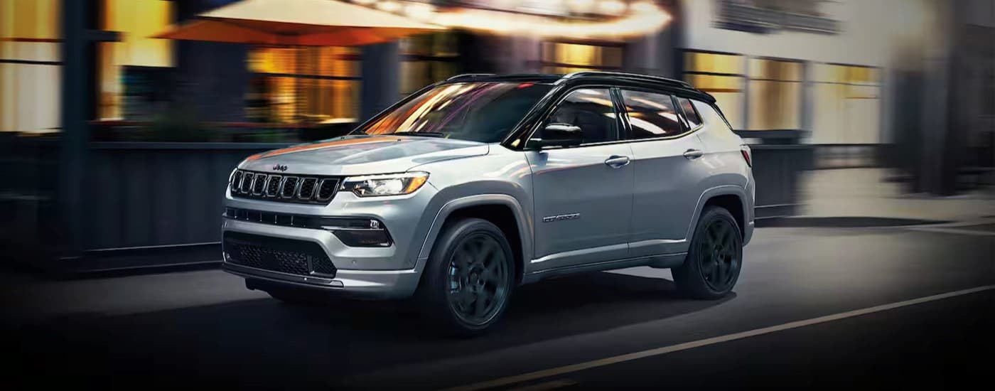 A silver 2024 Jeep Compass driving to visit a Jeep dealer in Houston.