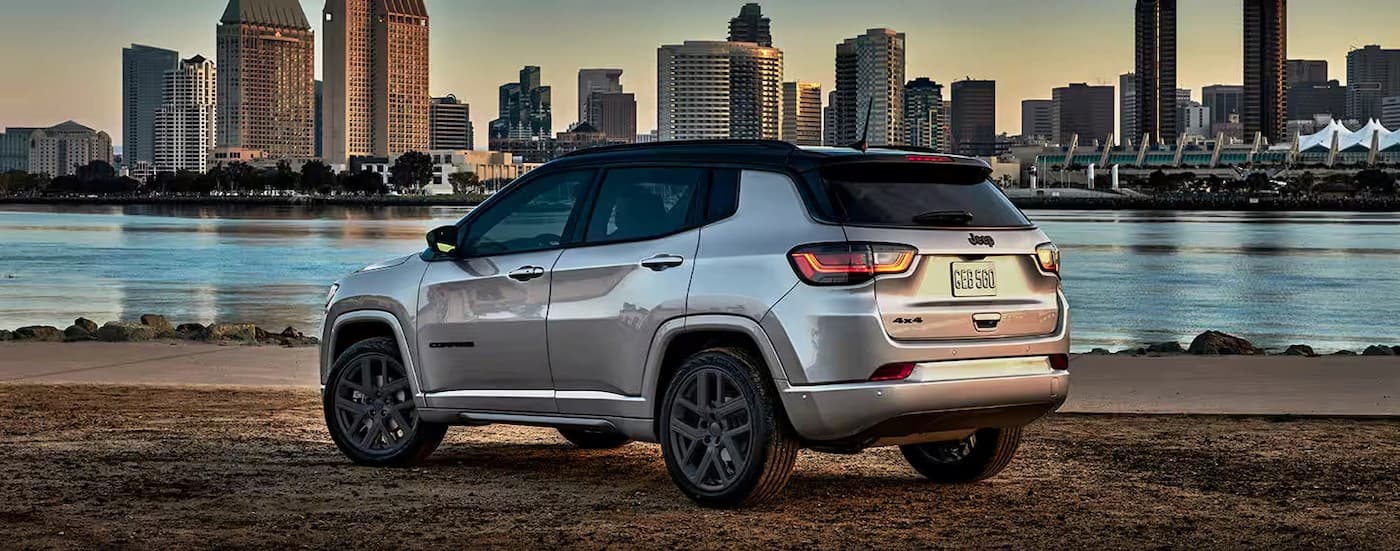 A silver 2024 Jeep Compass parked near a city.