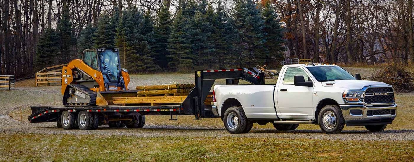 A white 2024 Ram 3500 towing a trailer after visiting a Ram dealer in Houston.