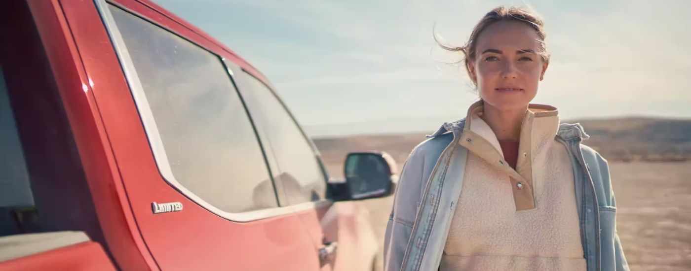 A person standing next to a red 2024 Toyota Tundra Limited.