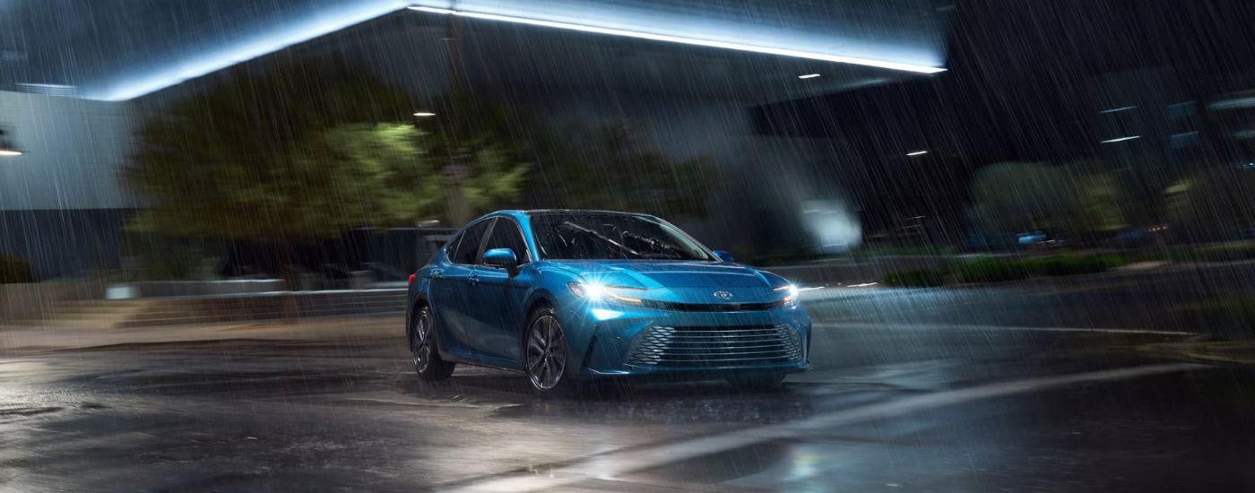 A blue 2025 Toyota Camry XLE driving on a rainy night.