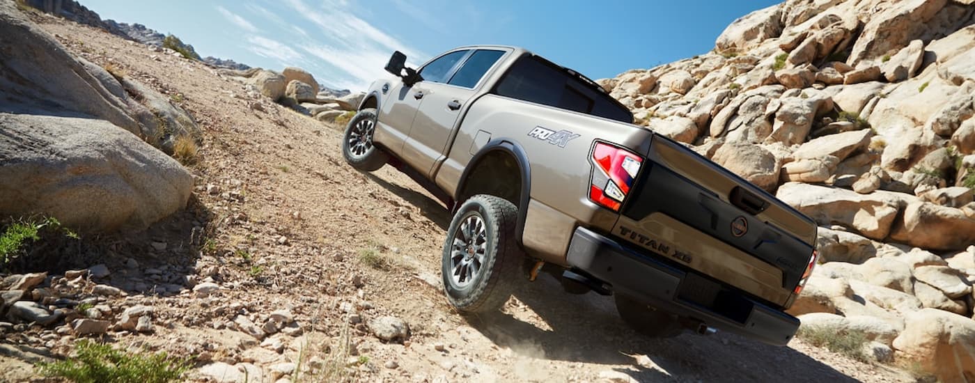 A brown 2024 Nissan Titan XD PRO-4X is driving up a steep rocky hill.