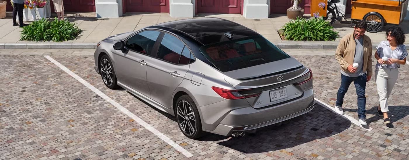 A silver 2025 Toyota Camry XSE is parked on the edge of a street.