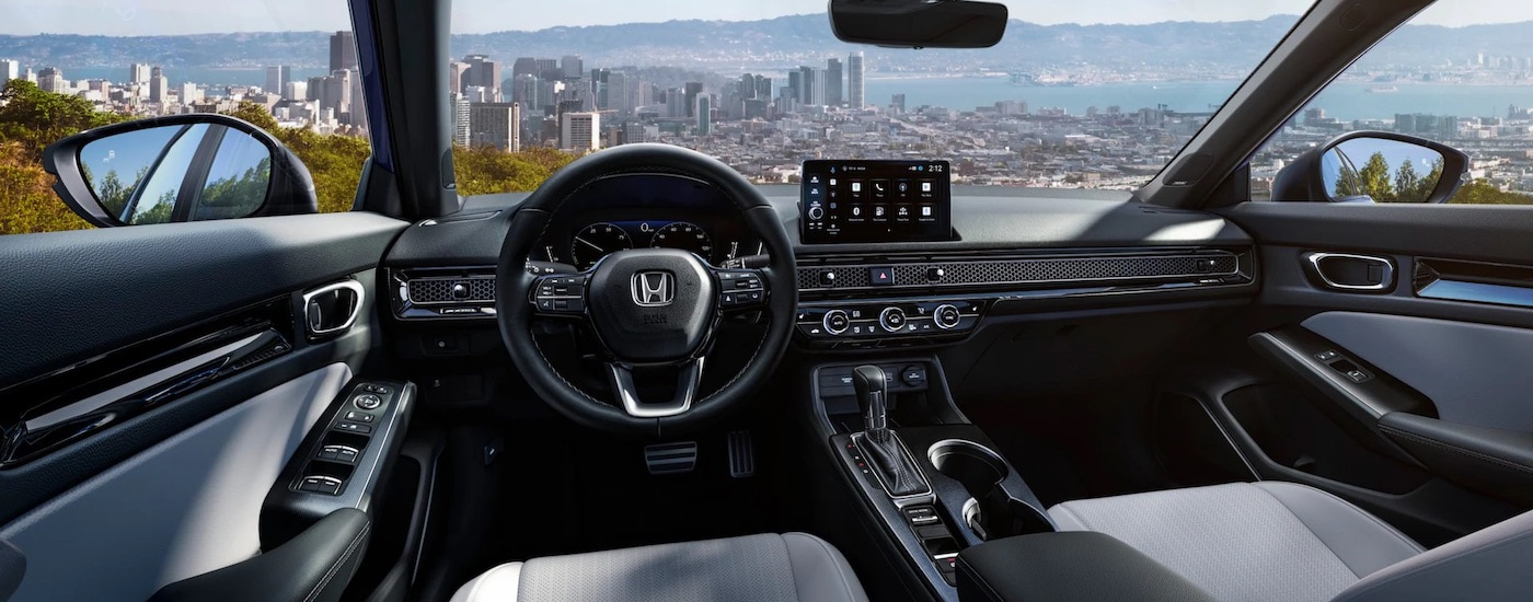 The interior of a 2024 Honda Civic Hybrid Sport Touring is shown from the driver's seat.