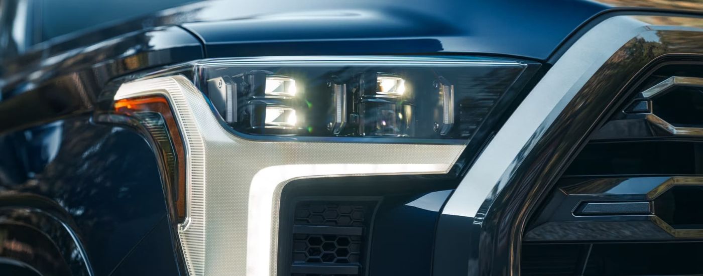 A close up shows the passenger side headlight on a blue  2024 Toyota Tundra.