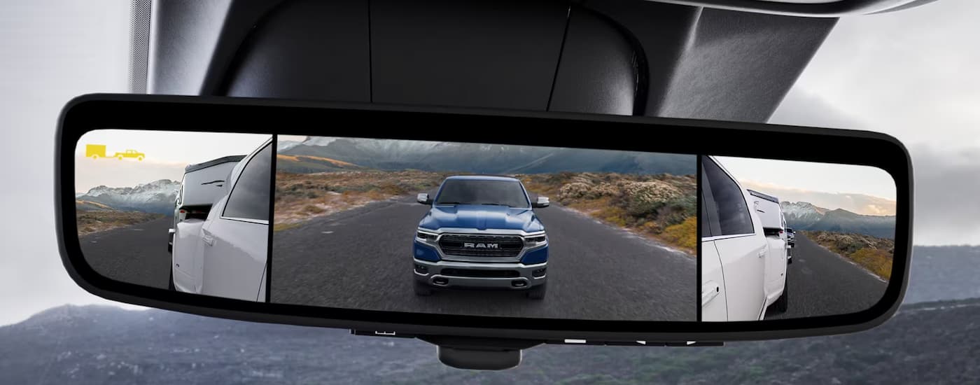 A blue Ram in the rearview mirror of a white 2024 Ram 3500HD.