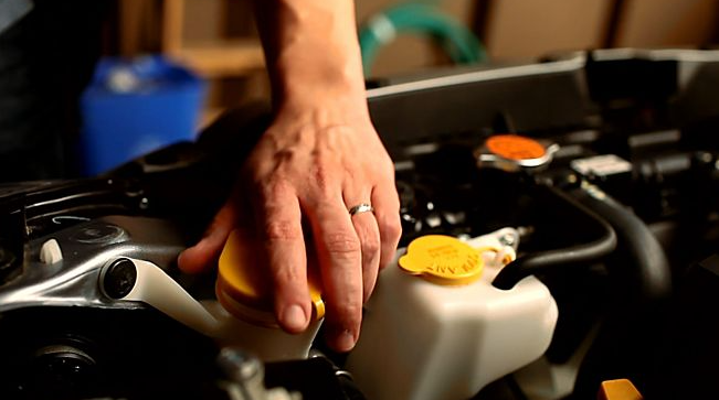 Close up of hand reaching towards a car engine