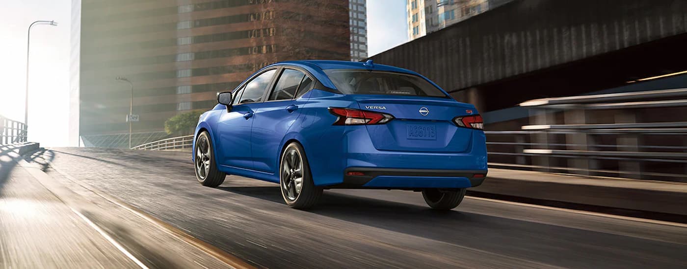A blue 2025 Nissan Versa SR is driving up a highway ramp.