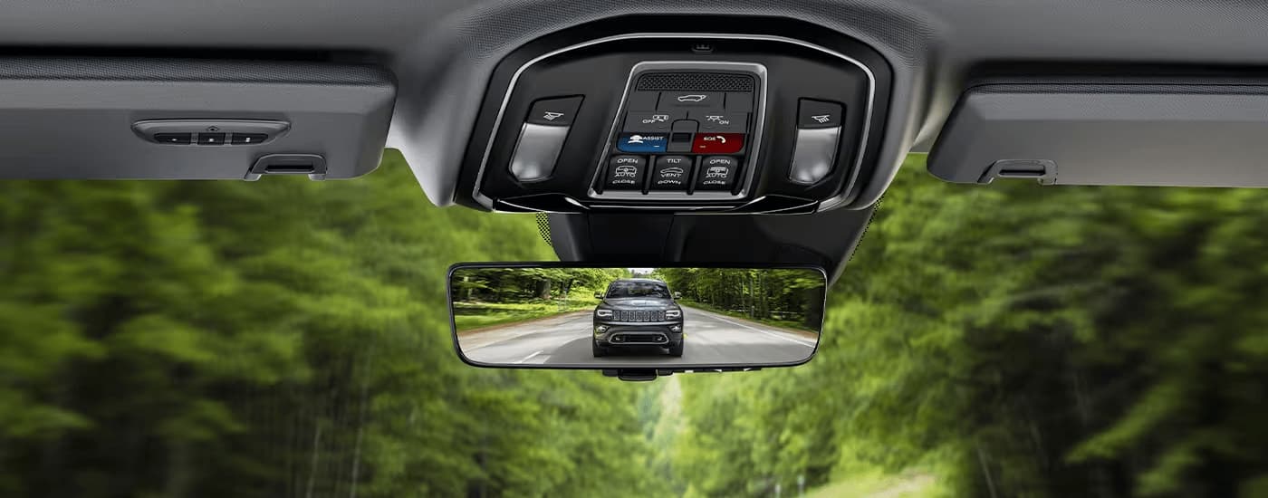 A close up of a grey 2023 Jeep Grand Cherokee L in the rearview mirror of a used Jeep for sale.